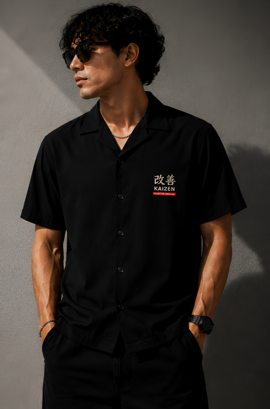 Man wearing a black shirt with a logo against a gray background